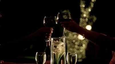 A couple is toasting with wine glasses at a table.