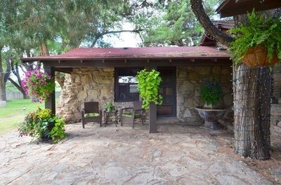 A stone house with a porch with chairs and plants