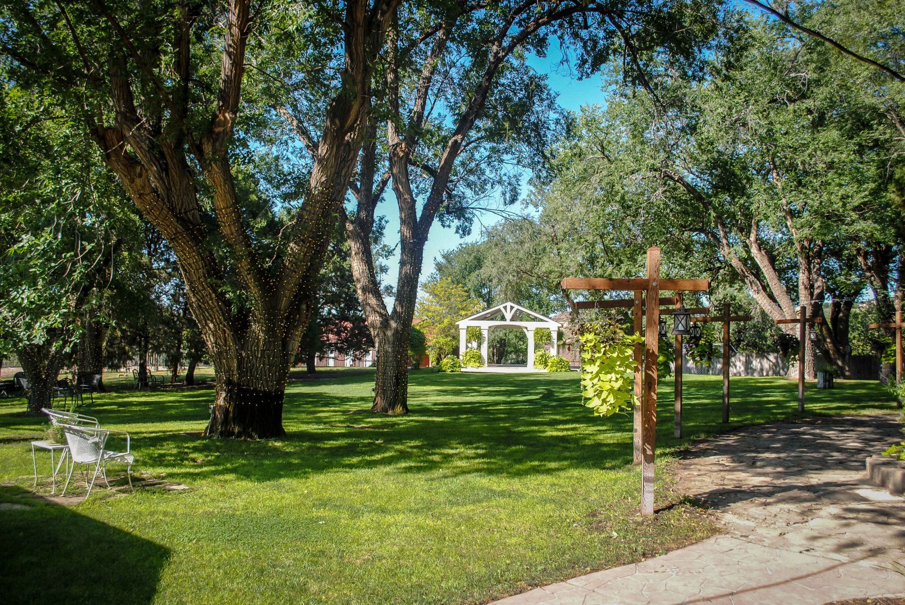 There is a white gazebo in the middle of the park surrounded by trees.