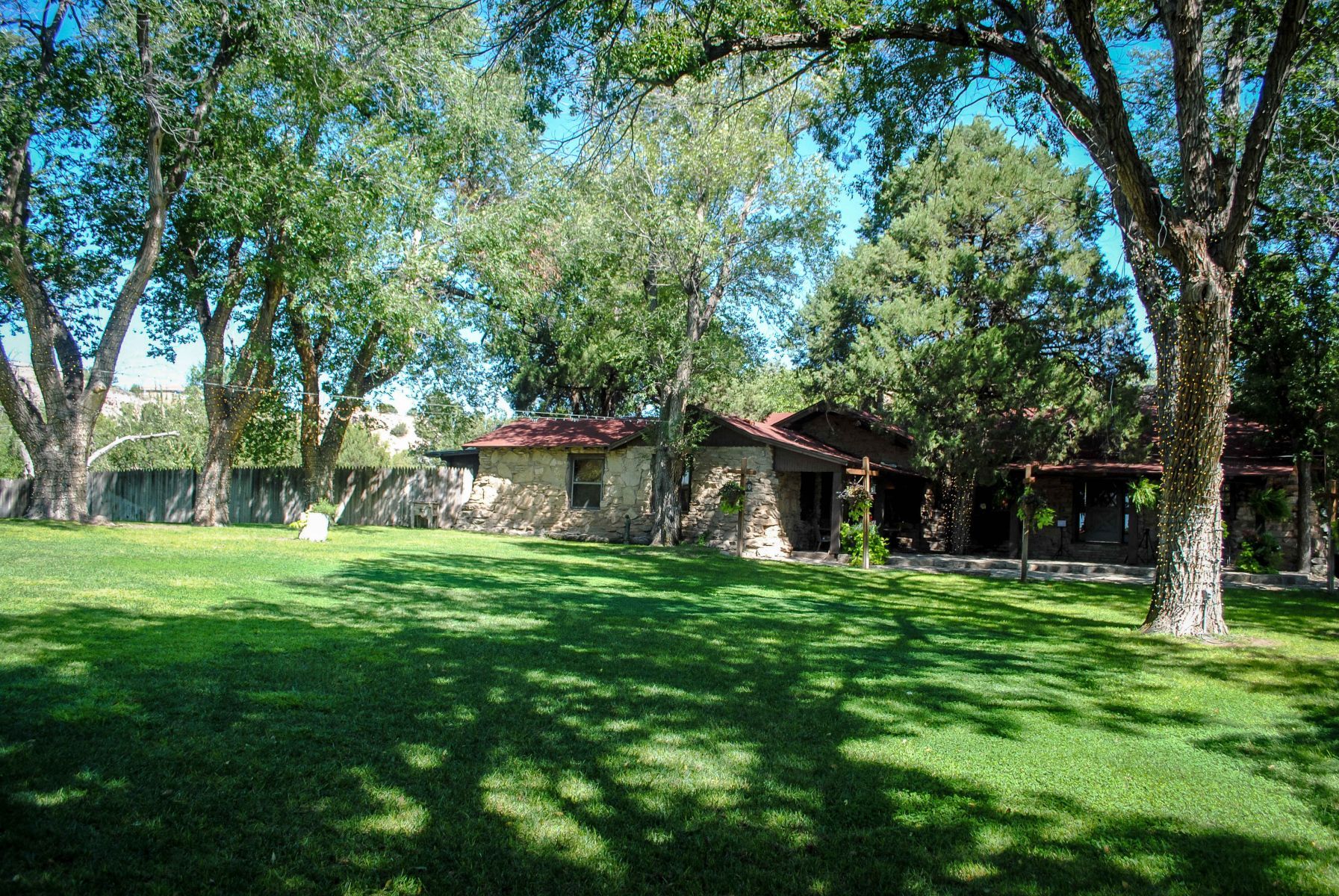 A house is sitting in the middle of a lush green field surrounded by trees.