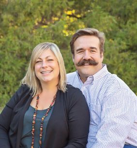 A man with a mustache and a woman are posing for a picture.