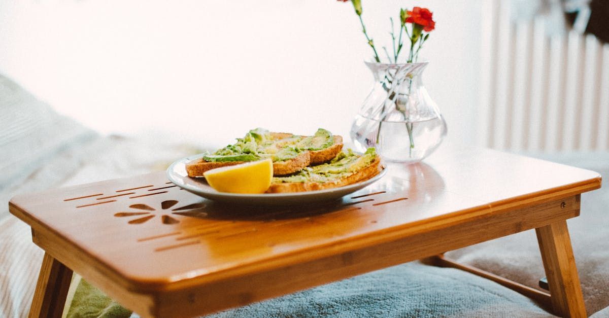 A wooden table with a plate of food and a vase of flowers on it.