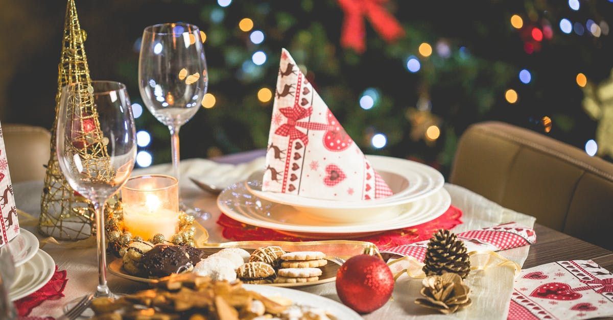 There is a christmas tree in the background and a table set for a christmas dinner.