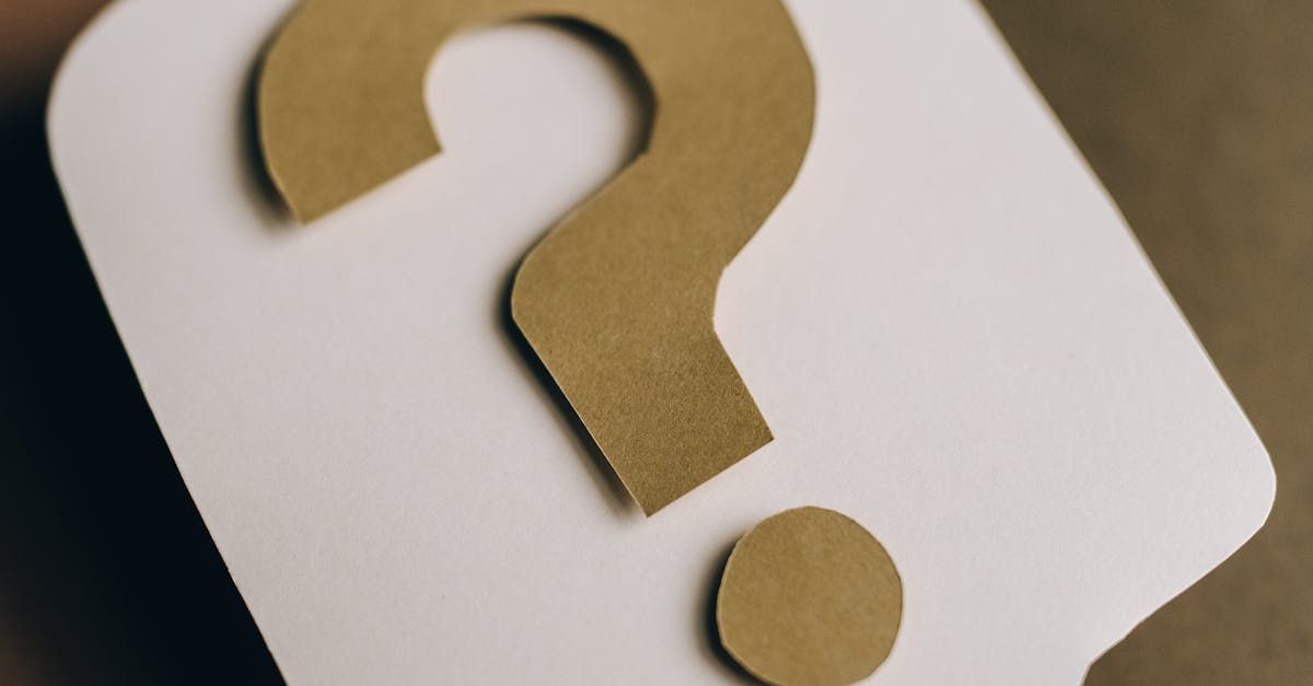 A question mark cut out of brown paper on a white card.