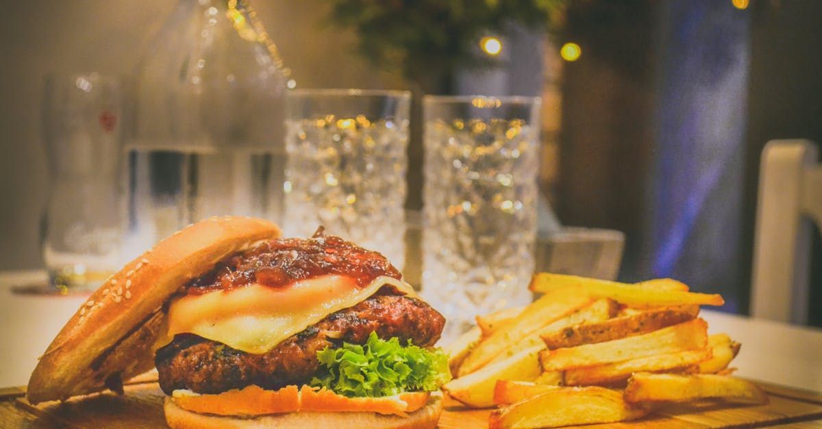 A hamburger and french fries are on a wooden cutting board on a table.