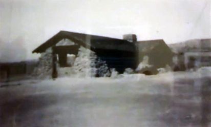 A black and white photo of a house in the snow.