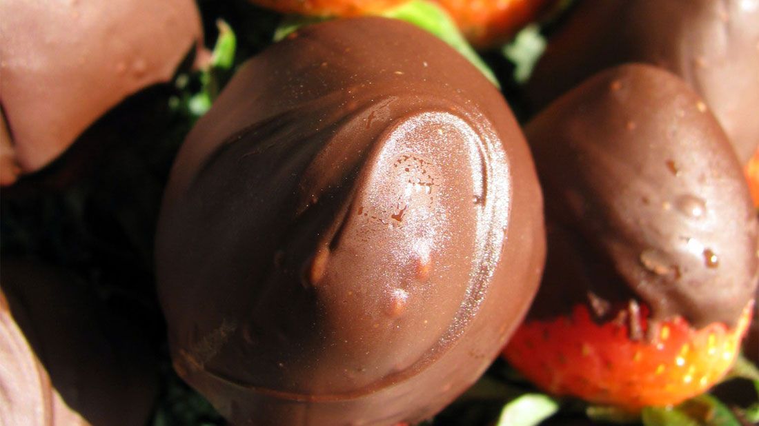 A close up of chocolate covered strawberries on a table