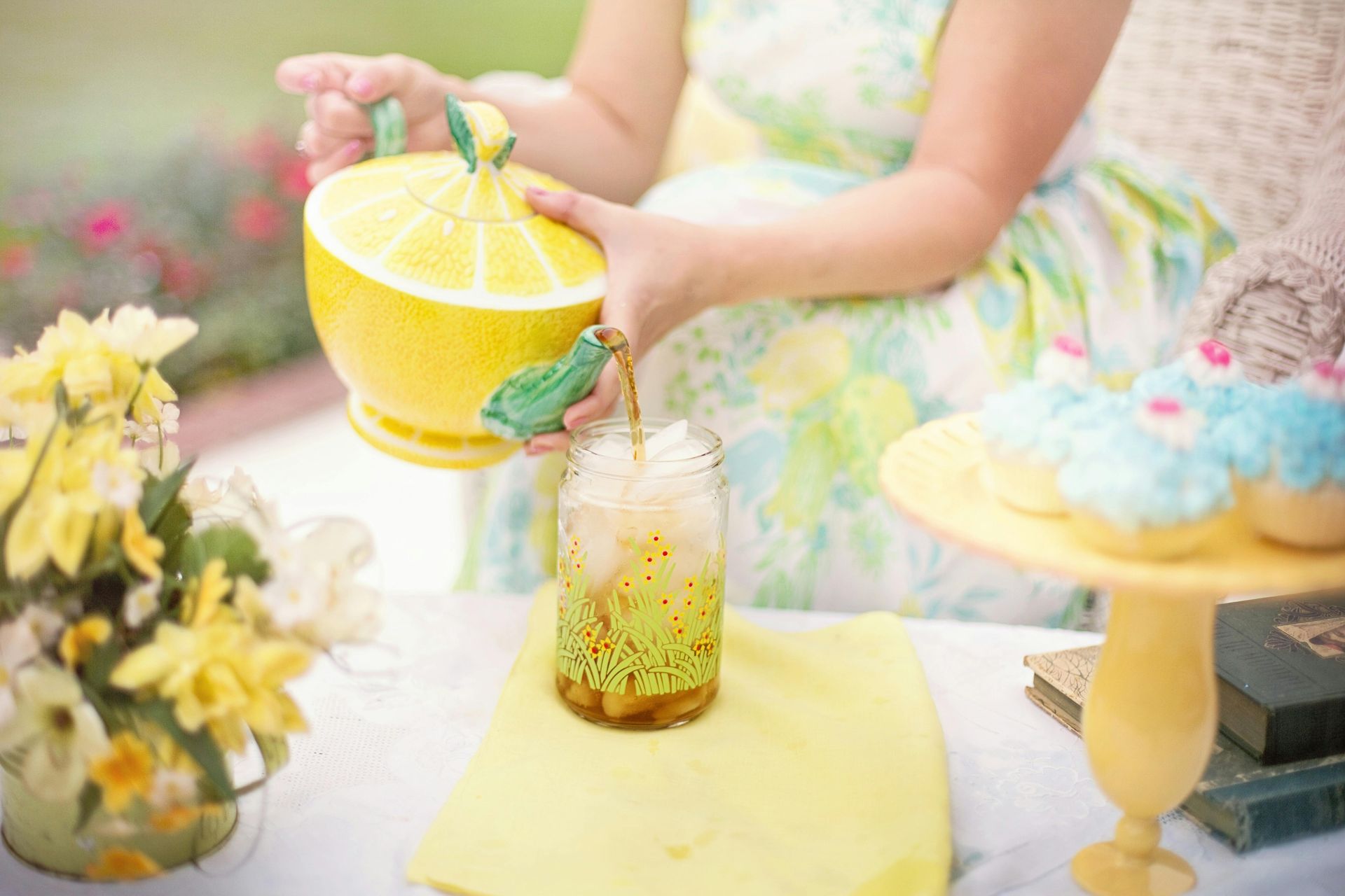 A woman is pouring lemonade into a mason jar.