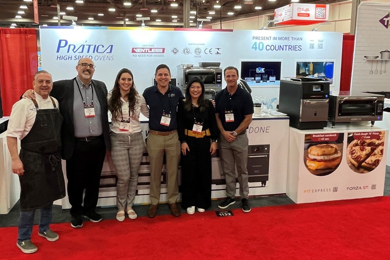 Um grupo de pessoas está posando para uma foto em frente a um estande em uma convenção.