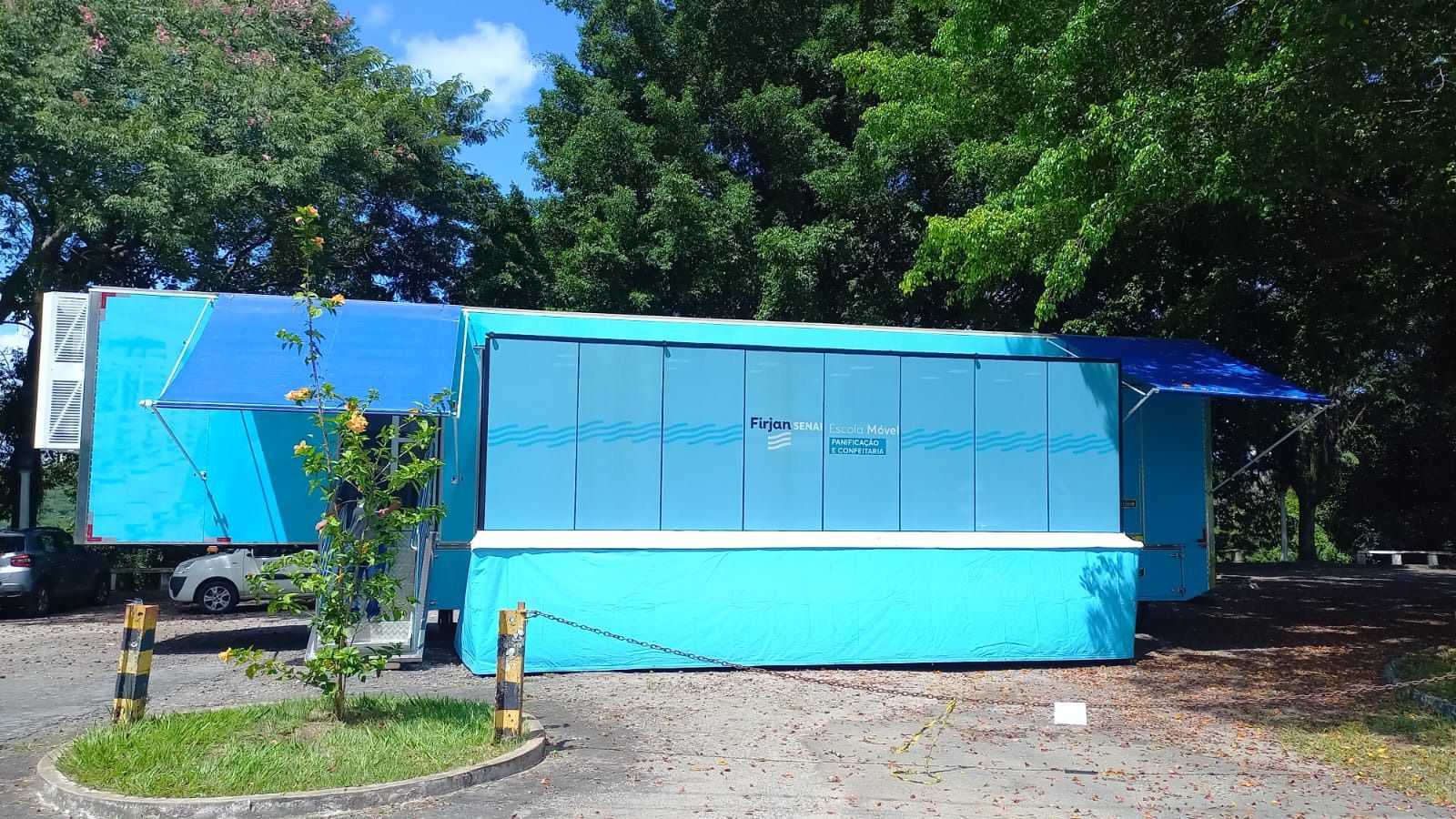 Um trailer azul com um toldo azul está estacionado em um estacionamento.