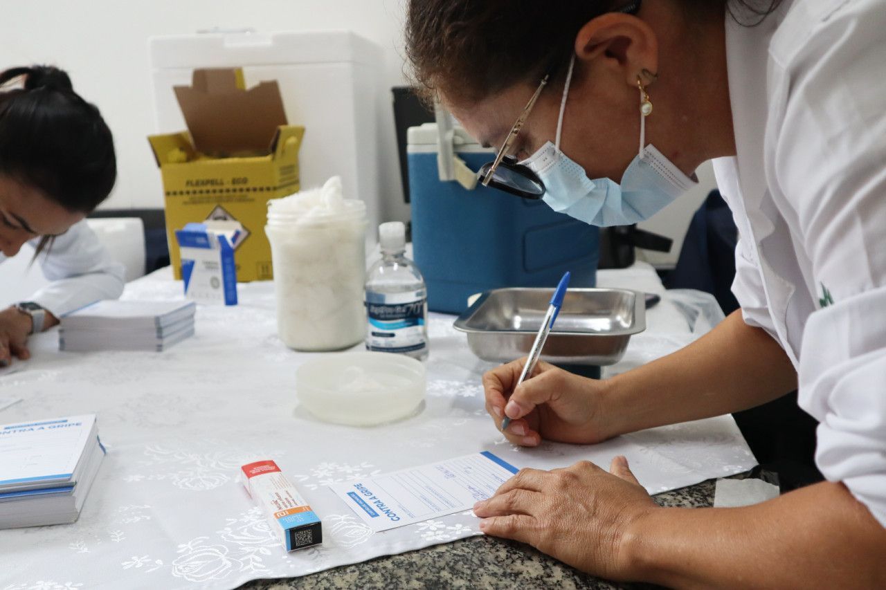 Uma mulher usando uma máscara está escrevendo em um pedaço de papel