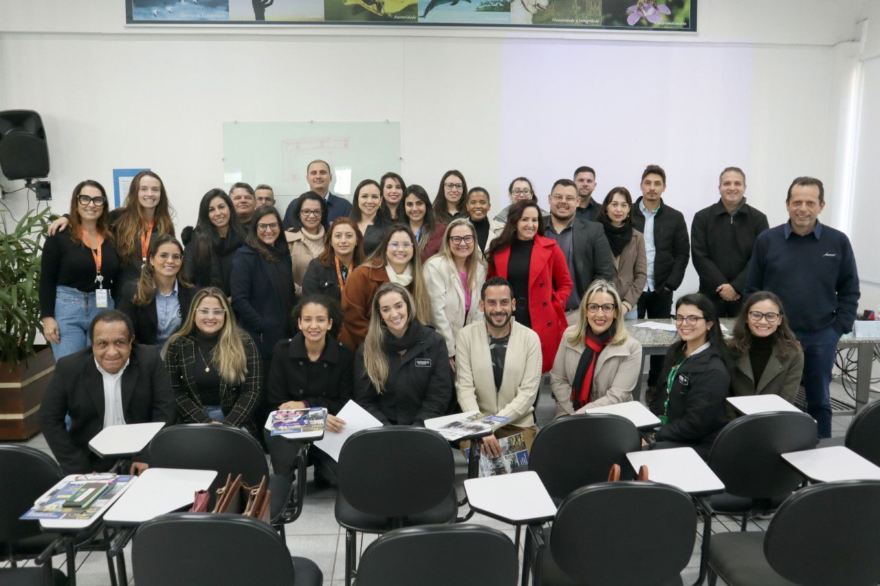 Um grupo de pessoas está posando para uma foto em uma sala de aula.