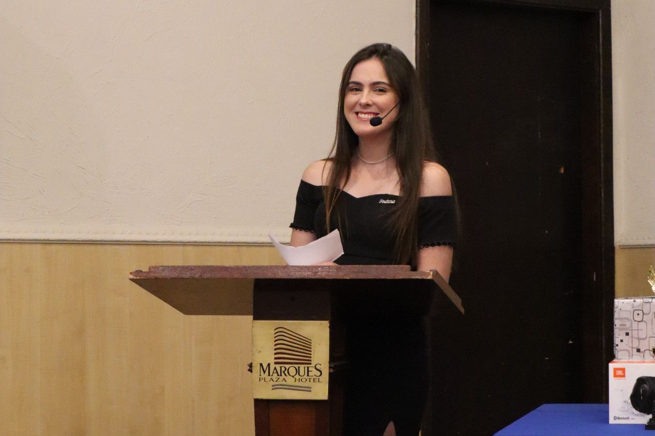 Uma mulher está de pé em um pódio com um microfone na cabeça.