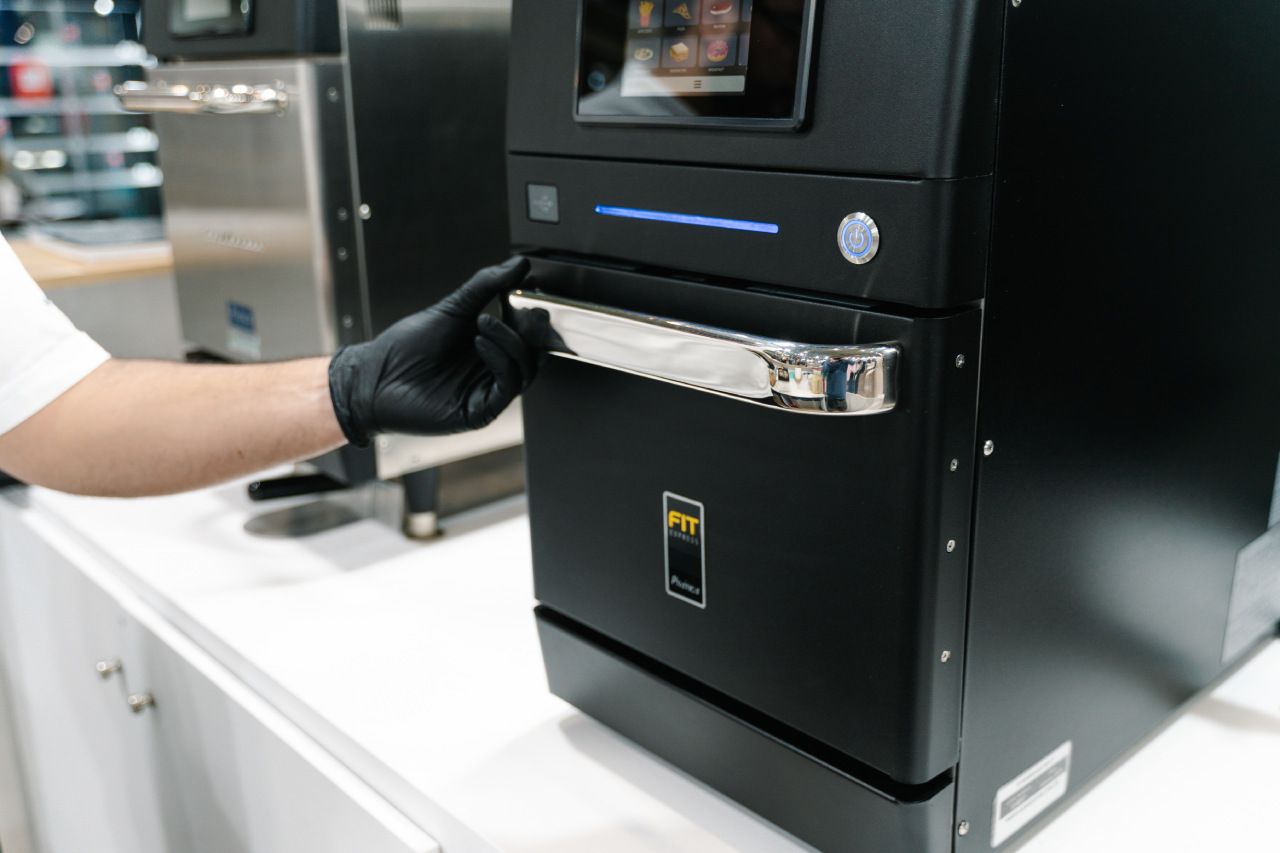 Uma pessoa usando luvas pretas está abrindo a porta de um forno preto.