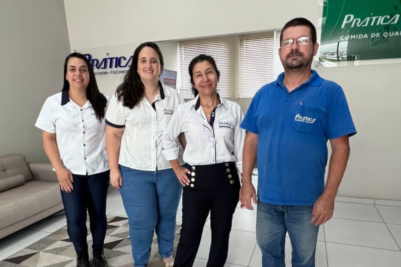 Um grupo de pessoas está posando para uma foto em frente a uma placa que diz pratica