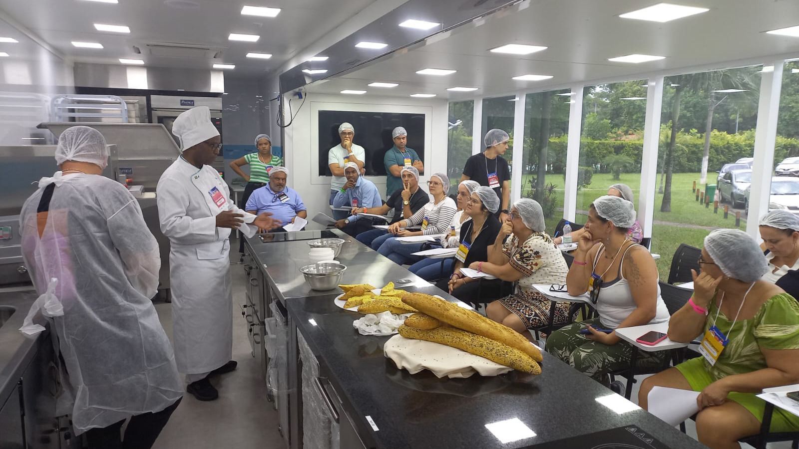 Um chef está fazendo uma apresentação para um grupo de pessoas em uma cozinha.
