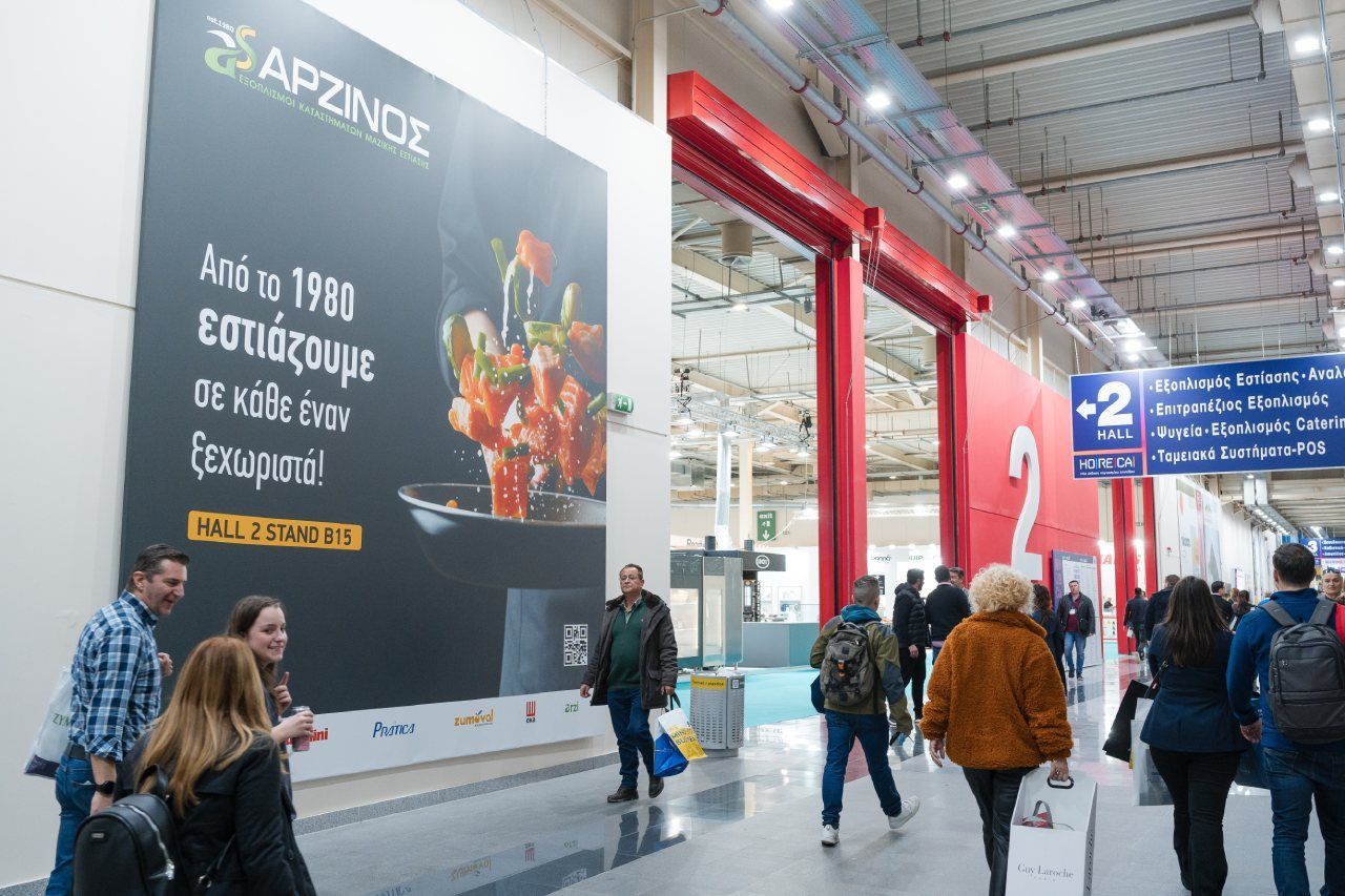 Um grupo de pessoas está caminhando em um prédio com uma grande placa na parede.