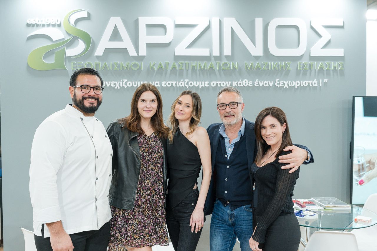 Um grupo de pessoas está posando para uma foto em frente a uma placa.