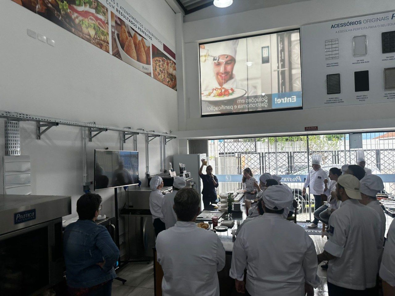 Um grupo de pessoas está em pé em frente a uma tela grande.