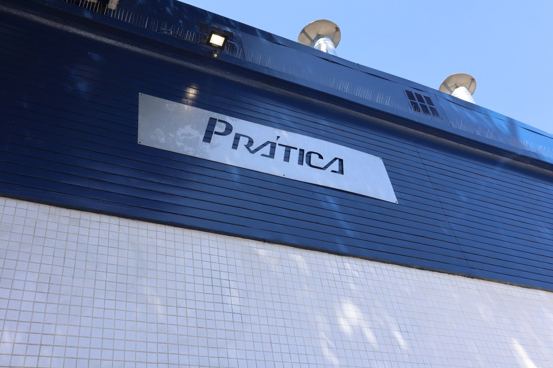 Uma placa na lateral de um prédio que diz prática