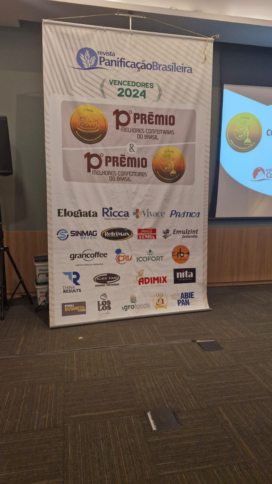 Um grande banner com logotipos está pendurado em uma sala.