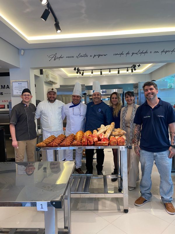 Um grupo de pessoas em pé em frente a uma mesa com comida.