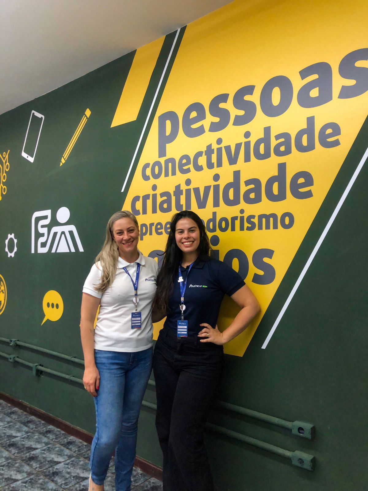 Duas mulheres em pé em frente a uma parede que diz pessoas