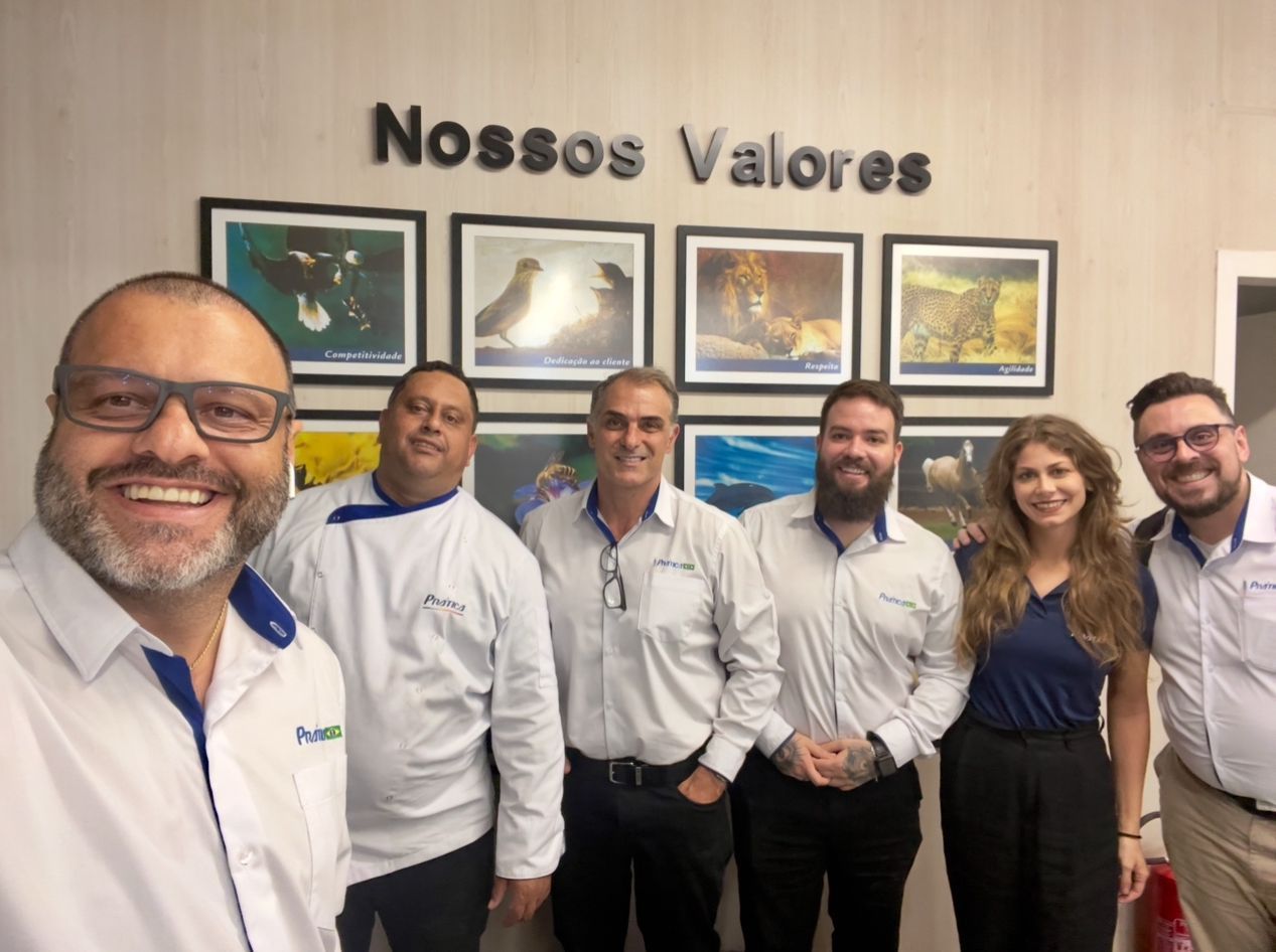 Um grupo de pessoas está posando para uma foto em frente a uma parede com fotos.
