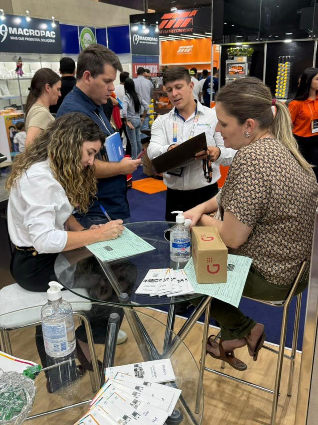 Um grupo de pessoas está sentado ao redor de uma mesa em uma convenção.