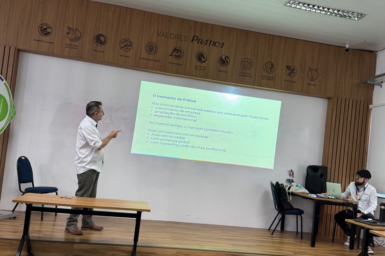 Um homem está em pé em frente a uma tela de projeção em uma sala de aula