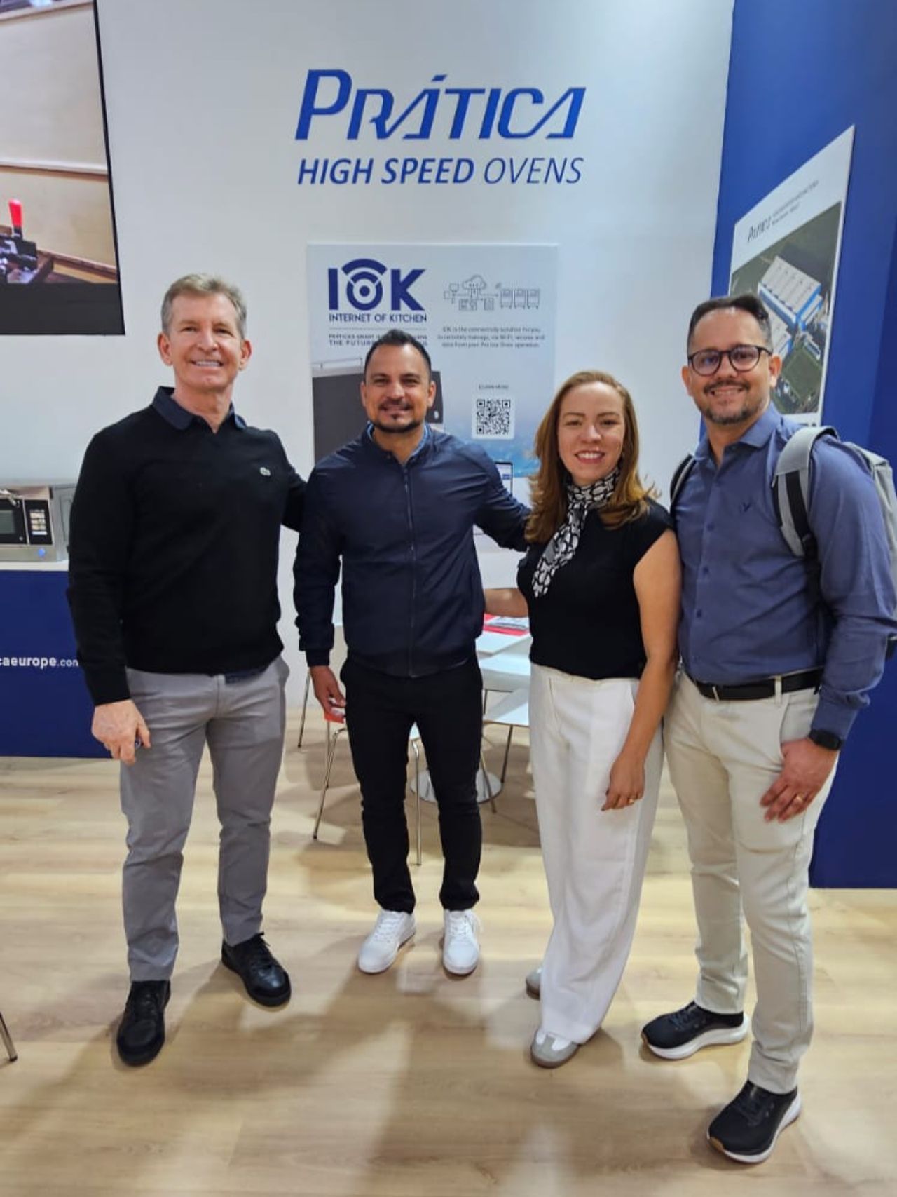 Quatro pessoas posam em frente a um expositor da 