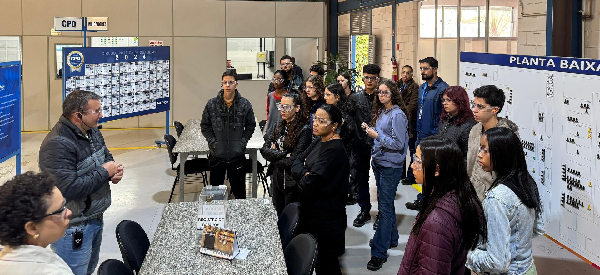 Um grupo de pessoas está em pé ao redor de uma mesa em uma sala.
