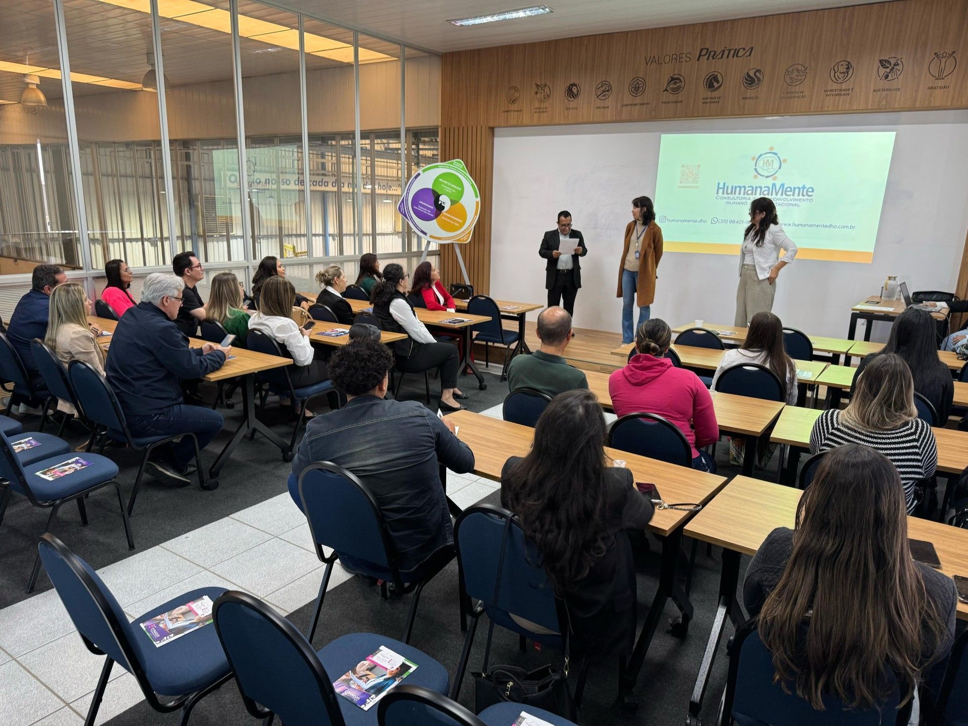 Um grupo de pessoas está sentado em carteiras em uma sala de aula.