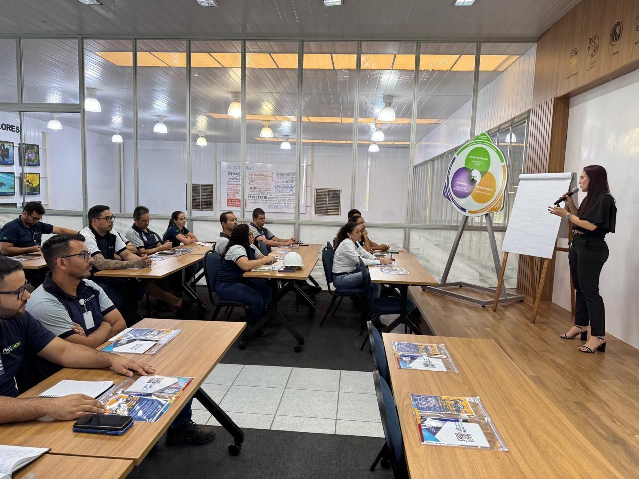 Uma mulher está fazendo uma apresentação para um grupo de pessoas em uma sala de aula.