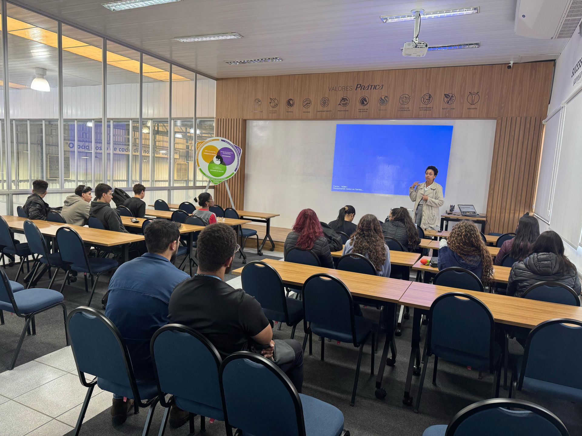 Um grupo de pessoas está sentado em mesas em uma sala de aula.