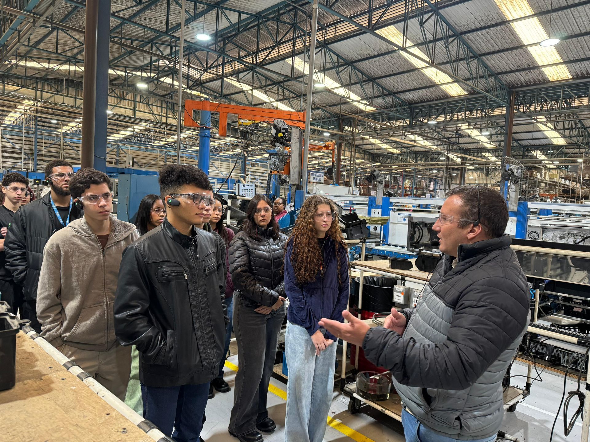 Um homem está conversando com um grupo de pessoas em uma fábrica.