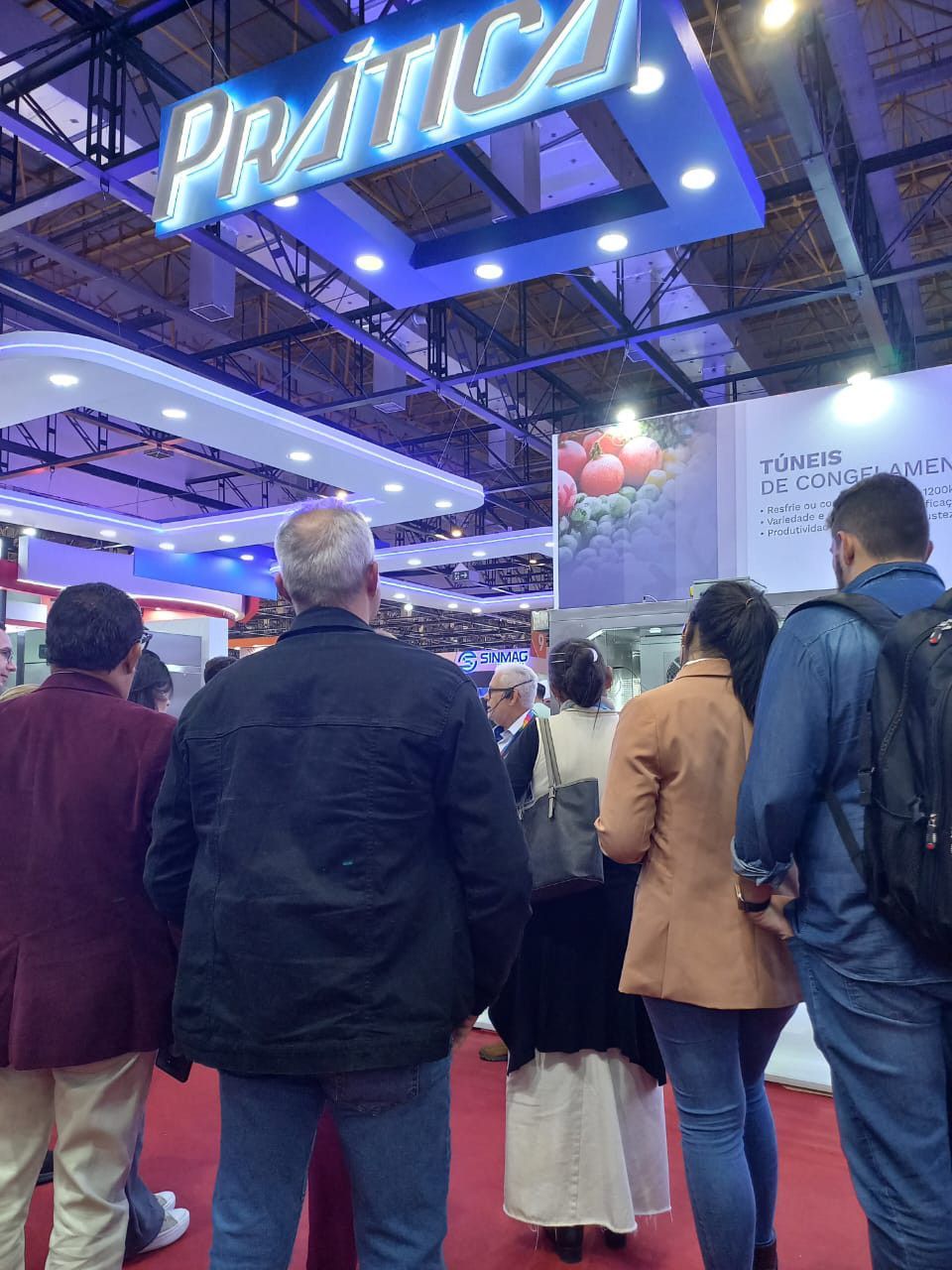 Um grupo de pessoas sob uma placa que diz prática