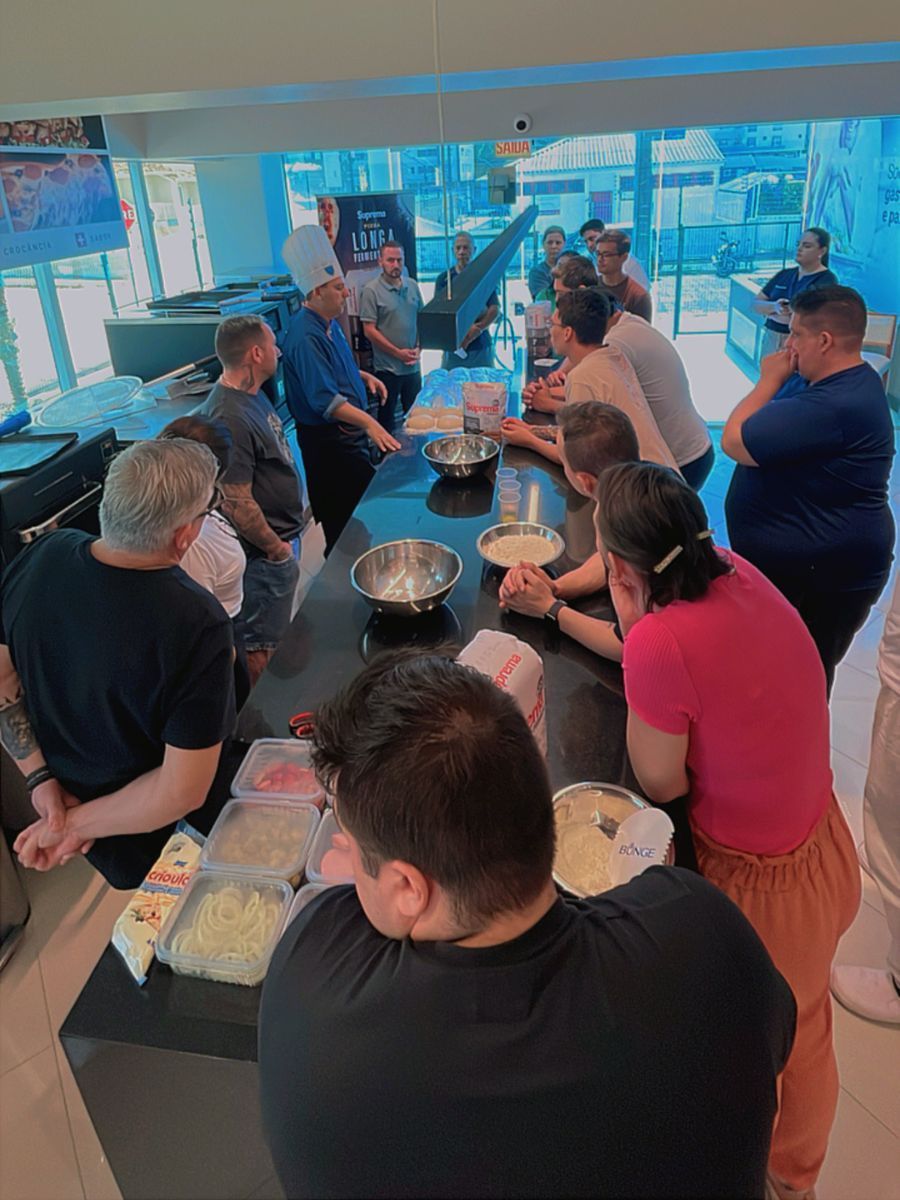 Um grupo de pessoas está sentado ao redor de uma mesa na cozinha.