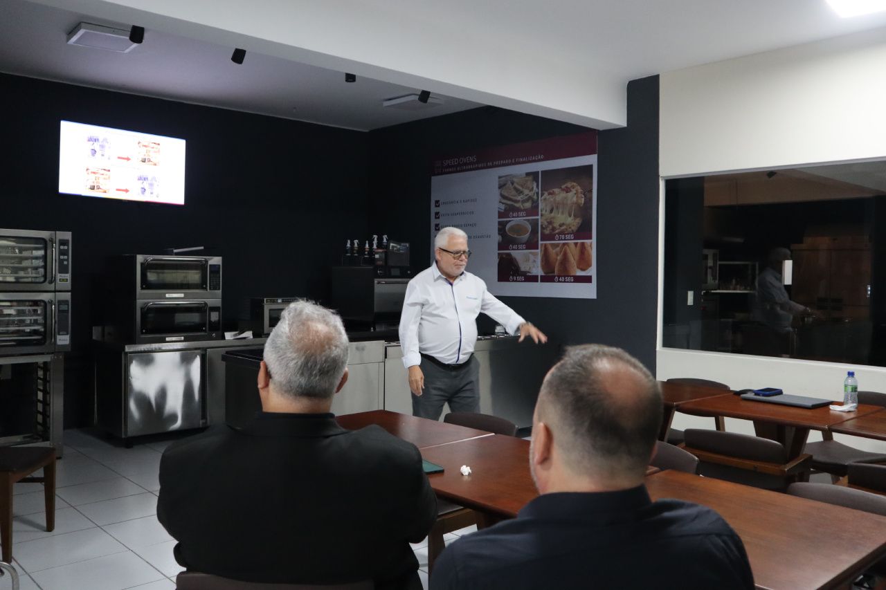 Um homem está fazendo uma apresentação para um grupo de homens sentados à mesa.