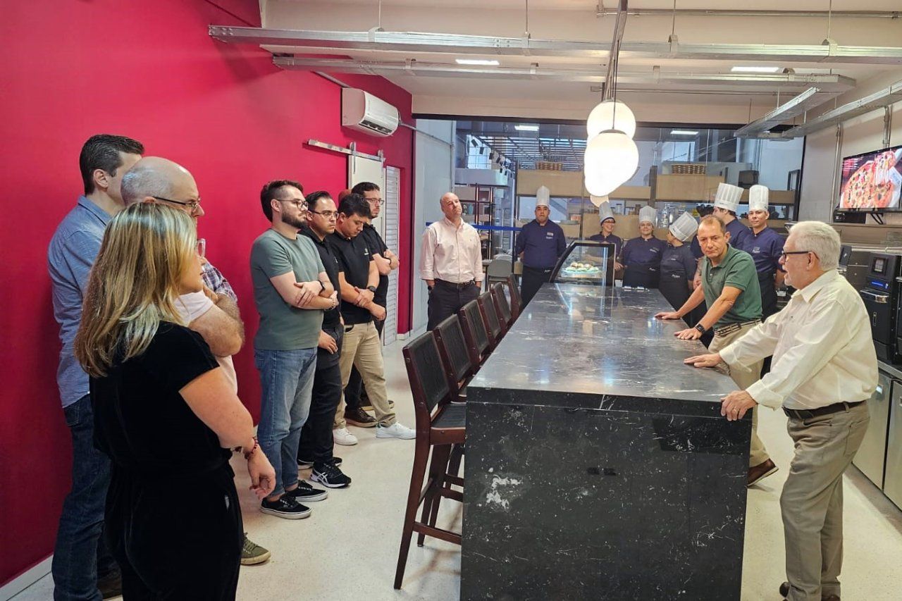 Um grupo de pessoas está em pé ao redor de um balcão na cozinha.