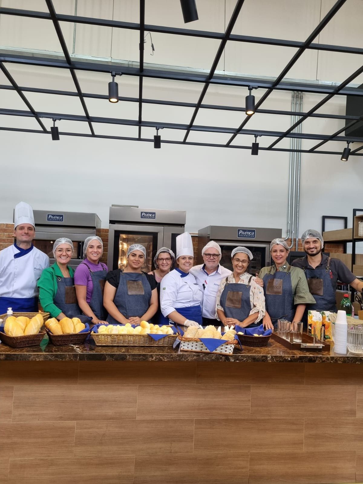 Um grupo de pessoas posa para uma foto em uma cozinha.