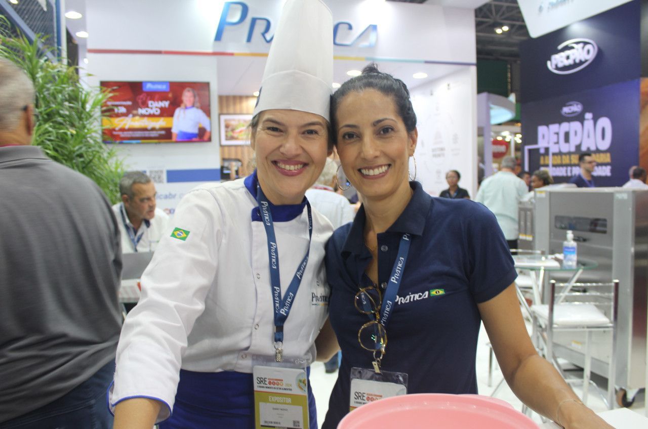 Duas mulheres posando para uma foto em frente a uma placa que diz pecao