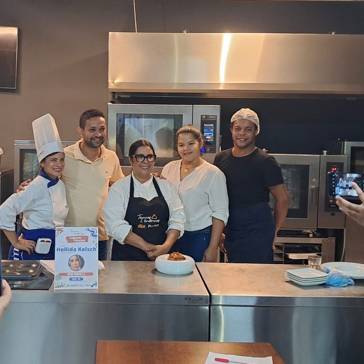 Um grupo de pessoas está posando para uma foto em uma cozinha