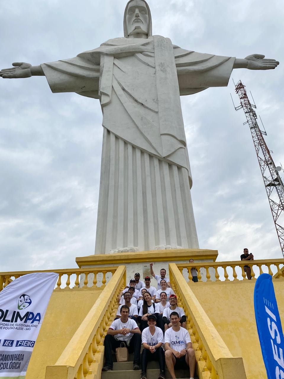 Um grupo de pessoas está posando para uma foto em frente a uma estátua de jesus