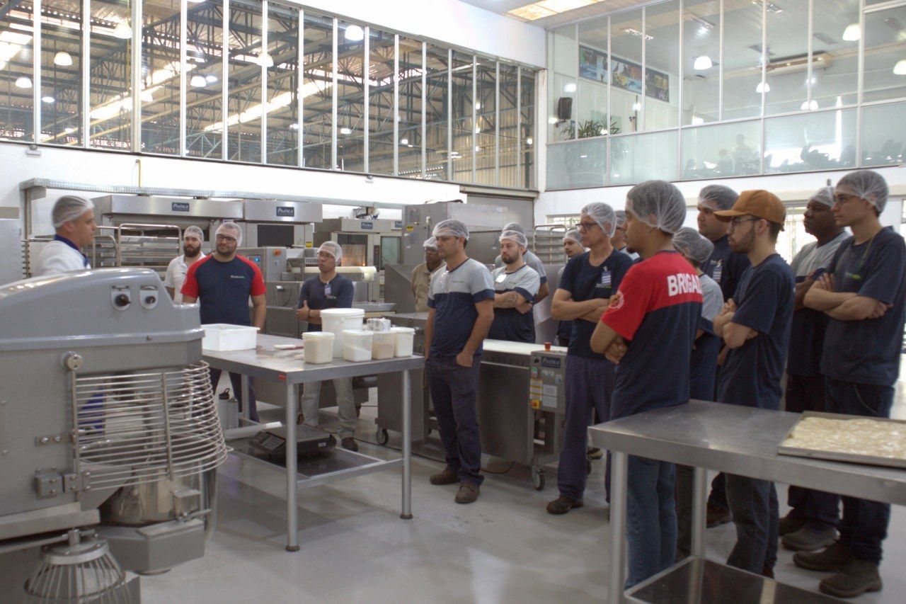 Um grupo de homens está em uma cozinha olhando para uma máquina.
