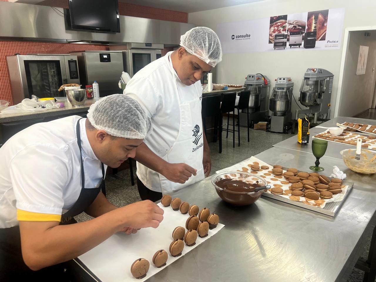 Dois homens estão trabalhando em uma cozinha preparando comida.