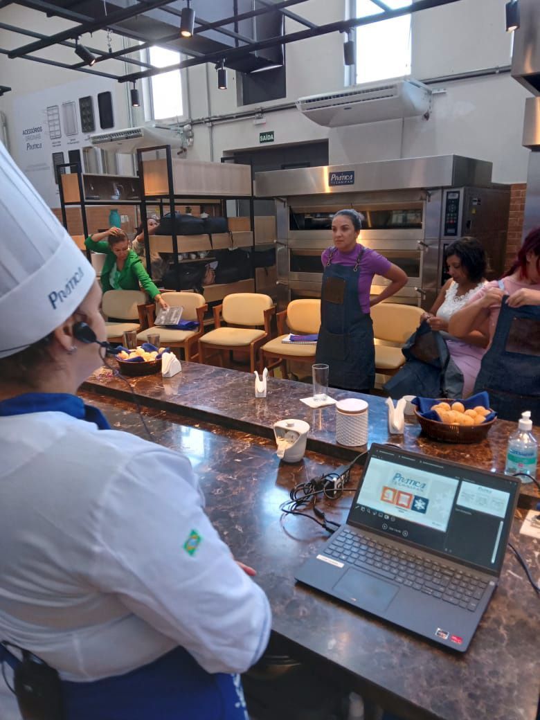 Um grupo de pessoas está em volta de uma mesa com um laptop em cima.