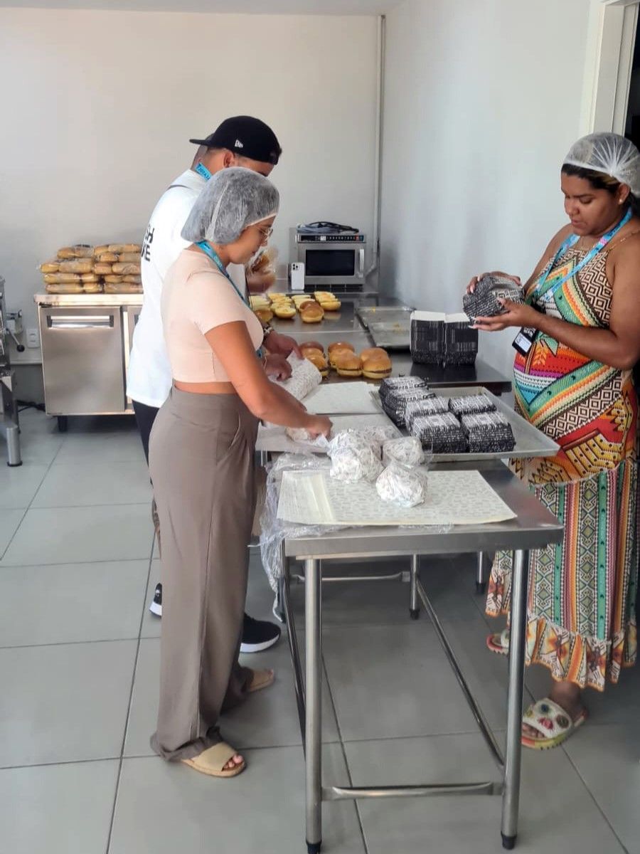 Um grupo de pessoas está trabalhando em uma cozinha preparando comida