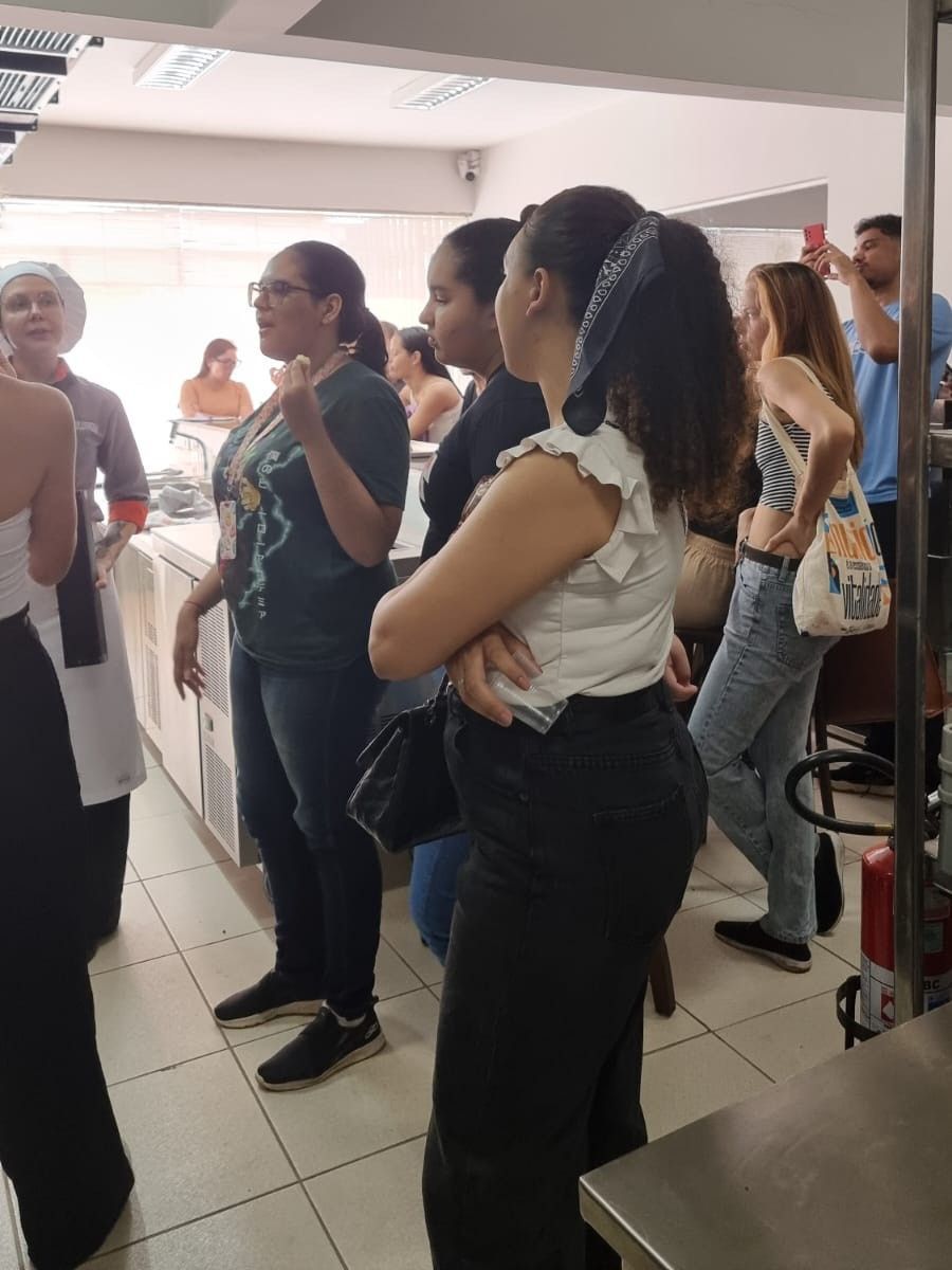 Um grupo de pessoas está em uma cozinha conversando entre si.