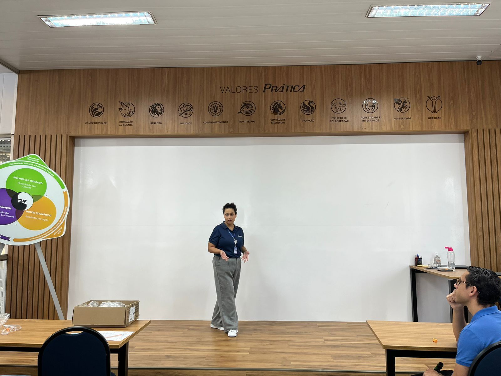 Uma mulher está de pé no palco em frente a um quadro branco.